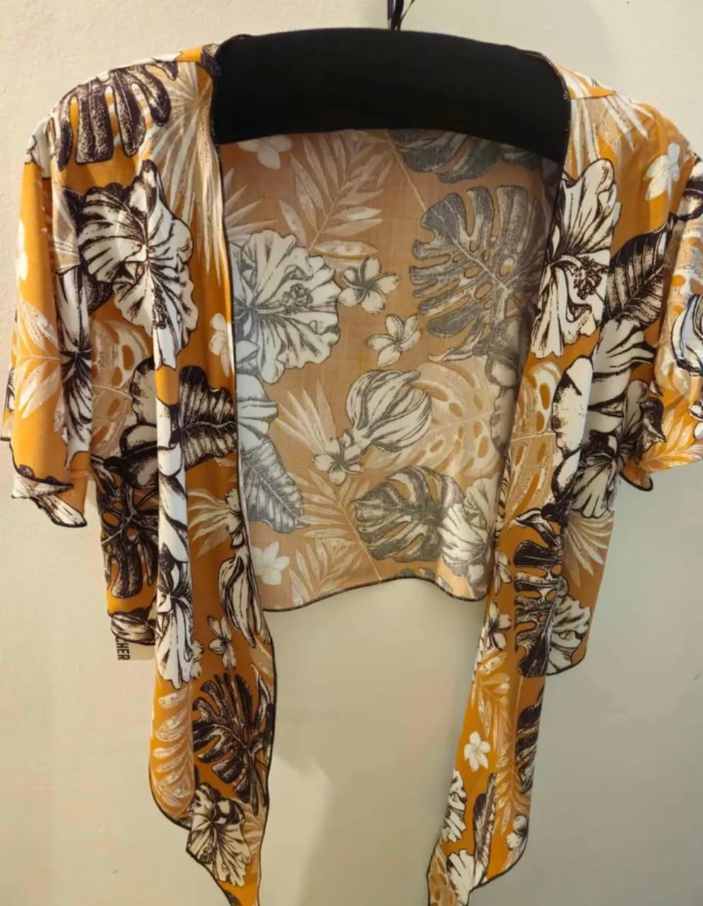 Kimono de tela liviana con estampado floral en tonos amarillos, blancos y negros. Ideal para usar sobre un top o traje de baño en verano. Marca Hecher.