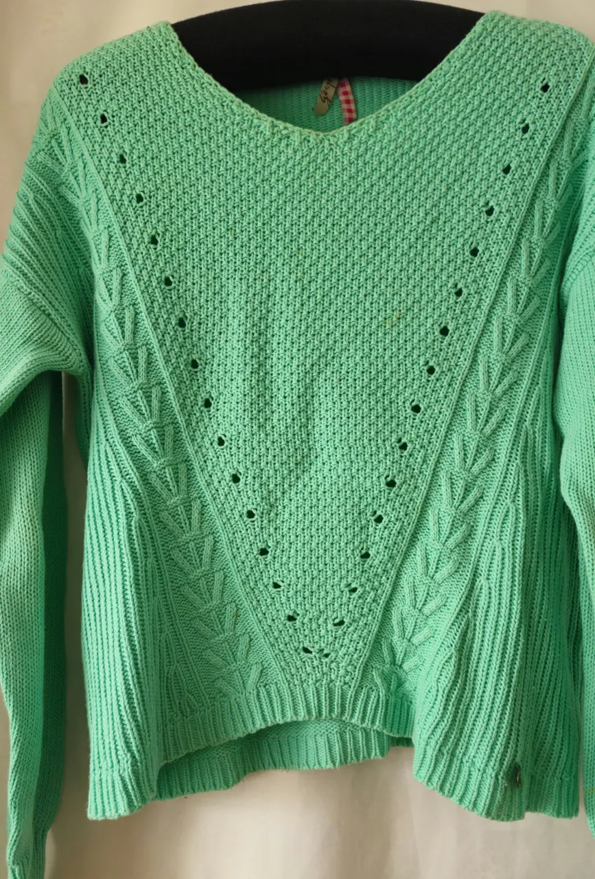 Sweater de punto verde con diseño en V en el frente. Ideal para un look casual y cómodo.