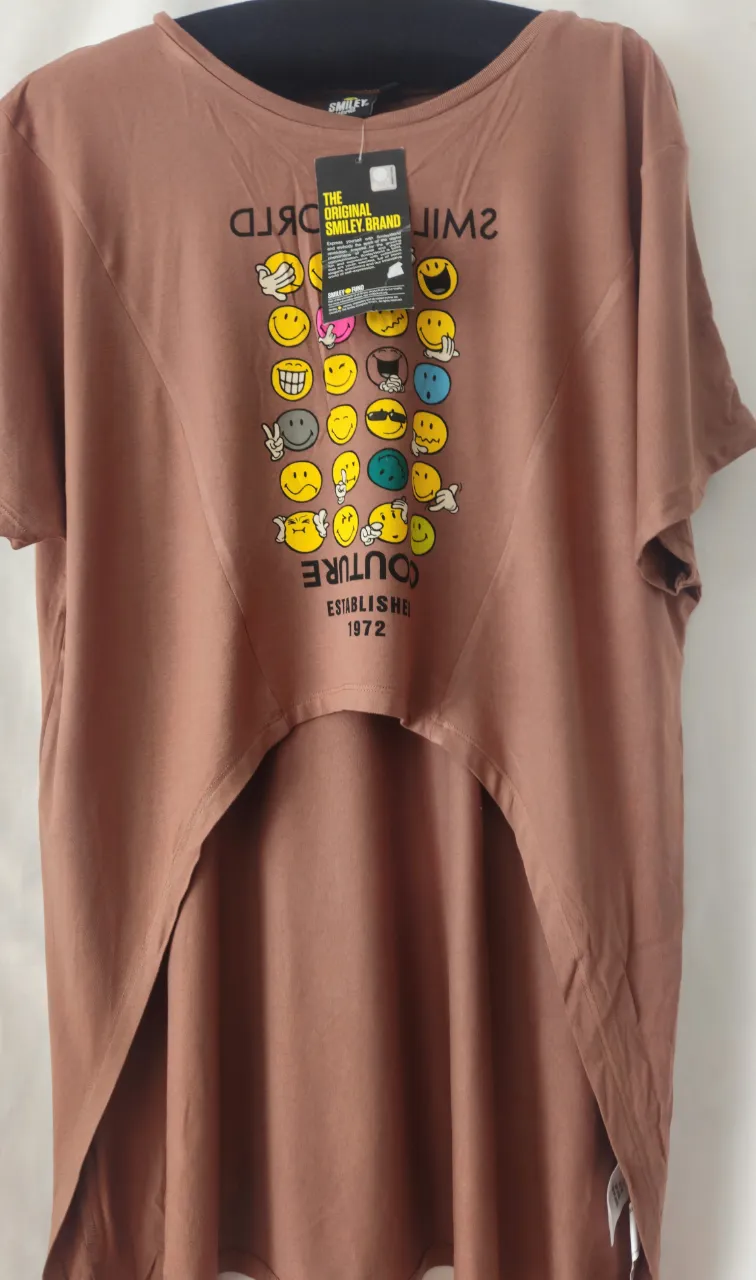 Remera de manga corta marrón con estampado de caritas sonrientes. Corte asimétrico con la parte trasera más larga. Ideal para un look casual y divertido. Madera interior Dubai.
