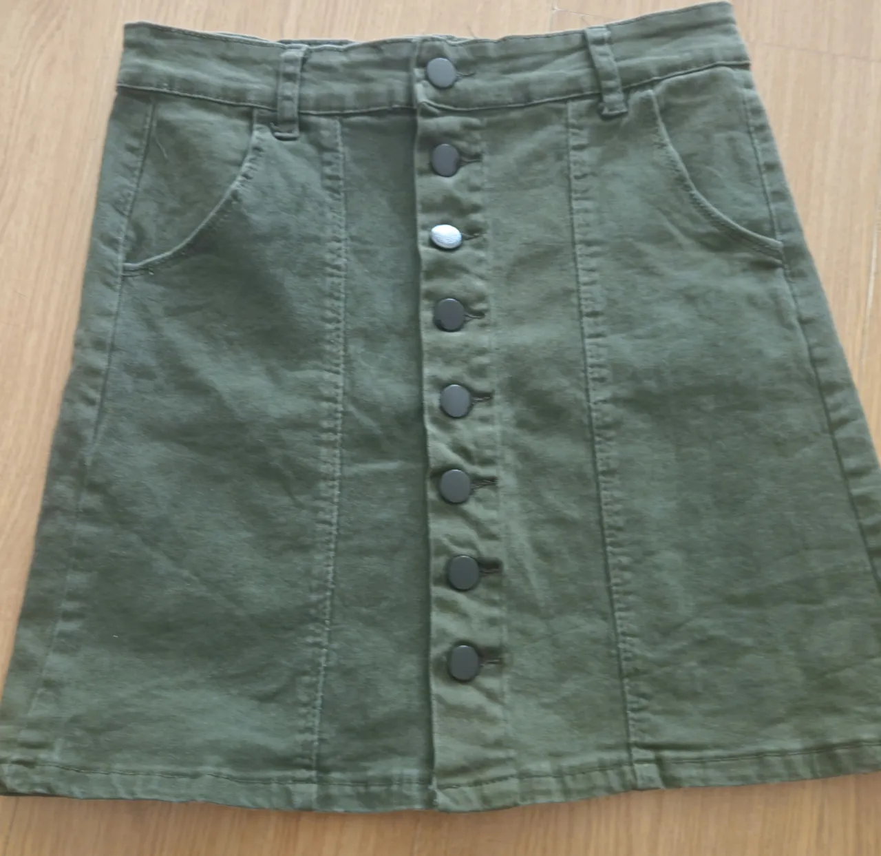 Pollera corta  de jean verde oscuro con botones delanteros. Ideal para un look casual y moderno. Medida 34 cm de cintura y 42 cm de largo.
