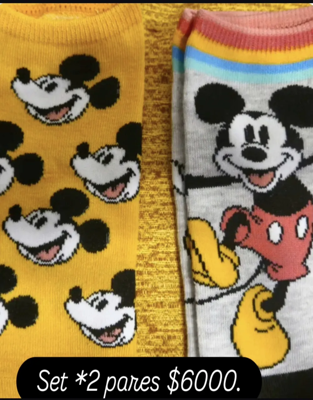 Set de dos pares de medias con estampa de Mickey Mouse. Un par es de color amarillo con múltiples estampas del personaje. El otro par es de color gris con una estampa grande de Mickey Mouse y detalles de colores en la parte superior.