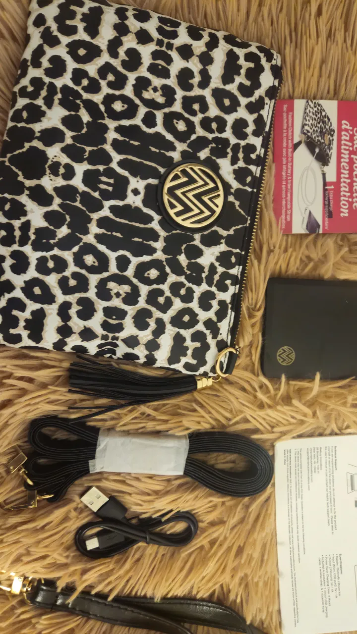 Cartera tipo sobre con estampado de leopardo en blanco y negro. Incluye correa para colgar y un llavero con borla. Ideal para llevar lo esencial con estilo. Cargador de teléfono, correa larga y corta.