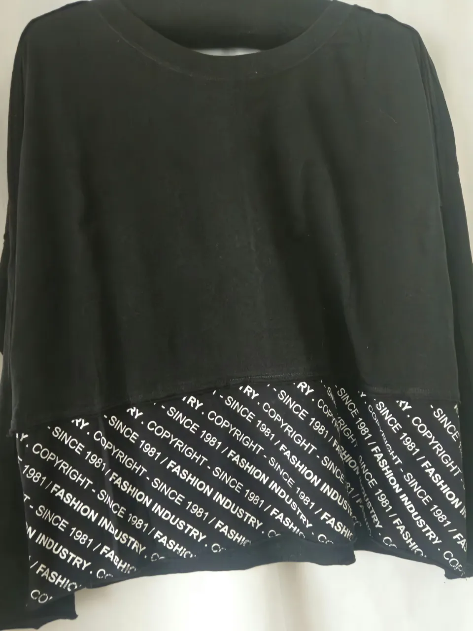 Buzo de cuello redondo negro con detalle estampado en blanco en la parte inferior. Diseño moderno y cómodo, ideal para un look casual y urbano.