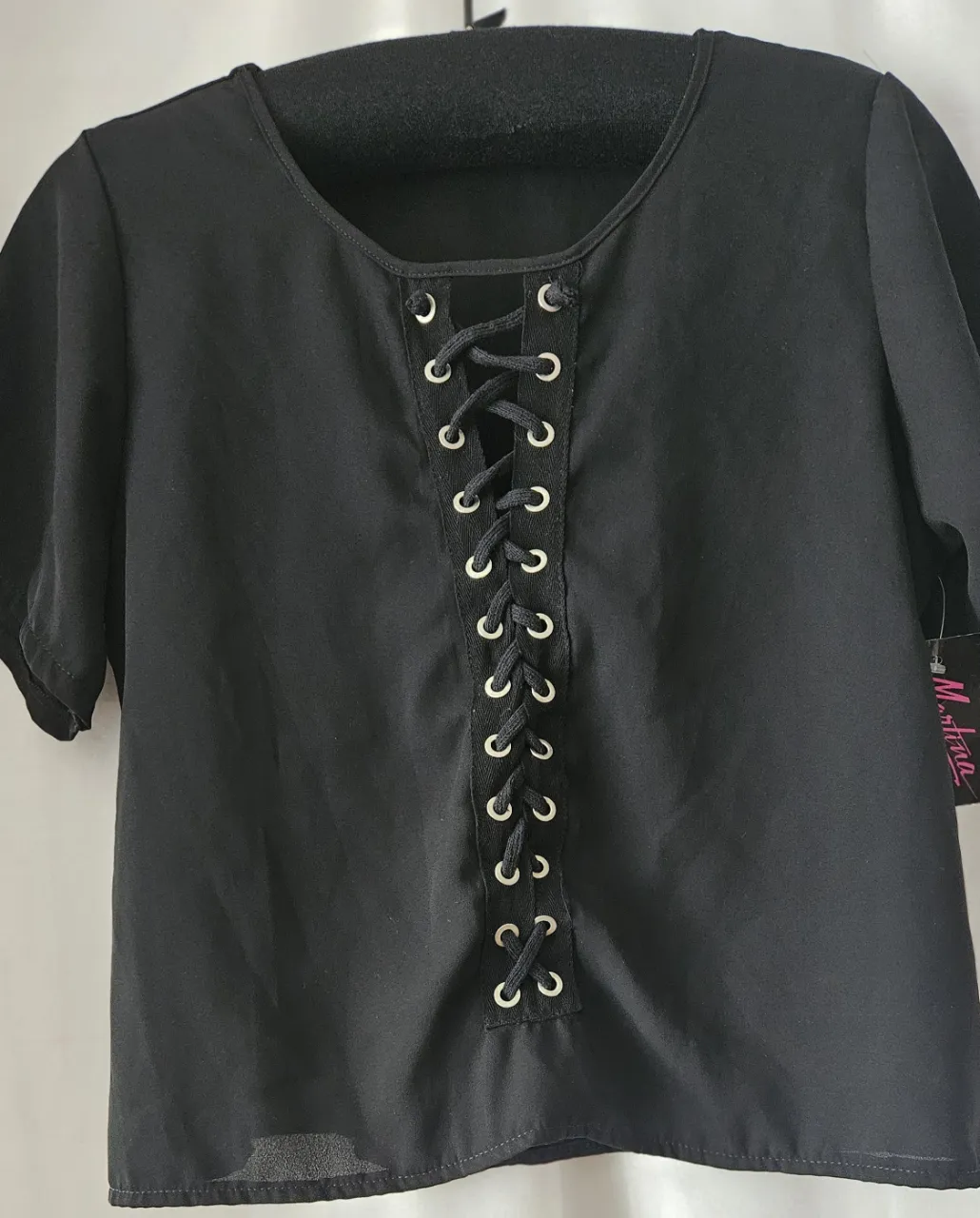 Blusa negra con detalle de cordones en el frente. Manga corta y cuello redondo. Ideal para un look casual o para salir.