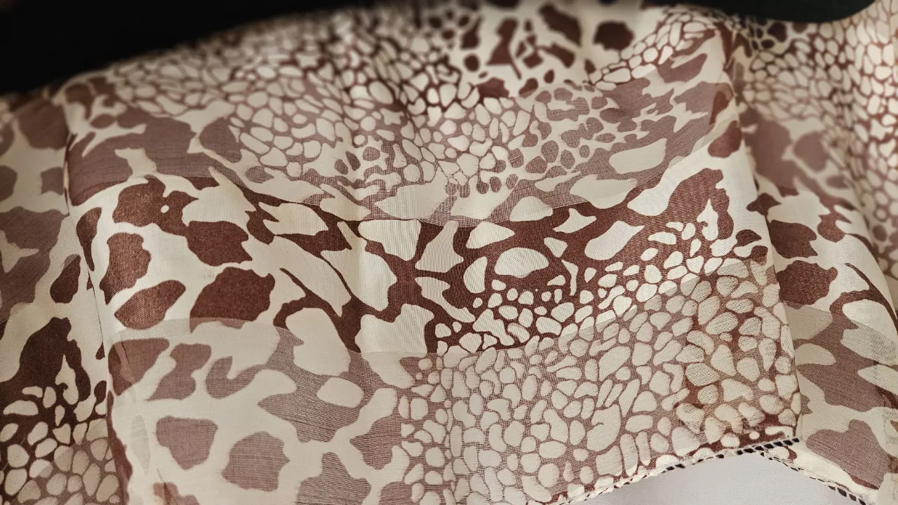 Pañuelo de seda con estampado animal print en tonos marrones y blanco. Ideal para complementar cualquier look. 145*35 cm.