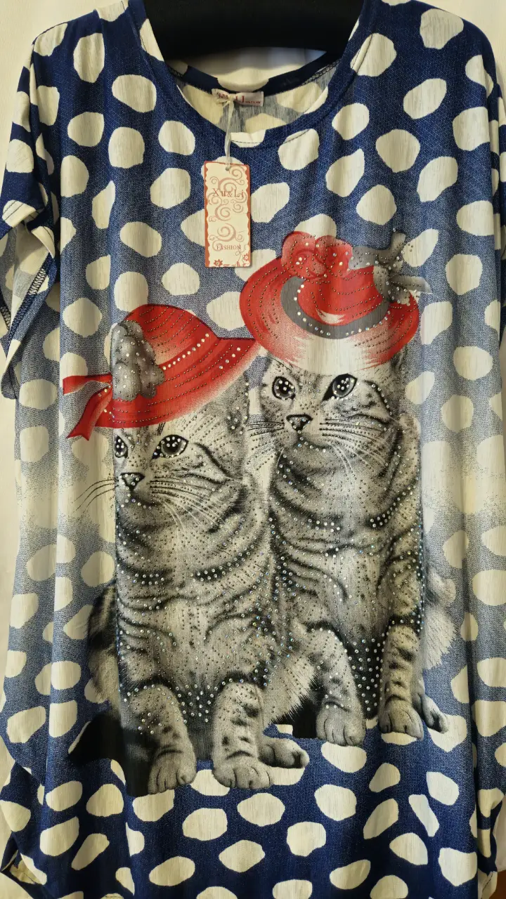 Blusa de mujer con estampado de gatos con sombreros rojos sobre fondo azul con lunares blancos. Ideal para un look casual y divertido.