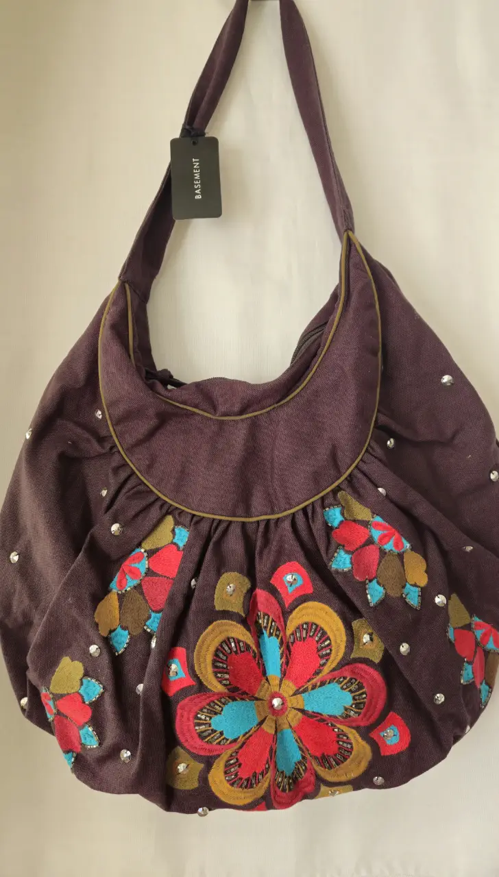 Bolso de hombro marrón con detalles florales bordados en rojo, azul y amarillo. Detalles de strass. Ideal para un look casual y bohemio.