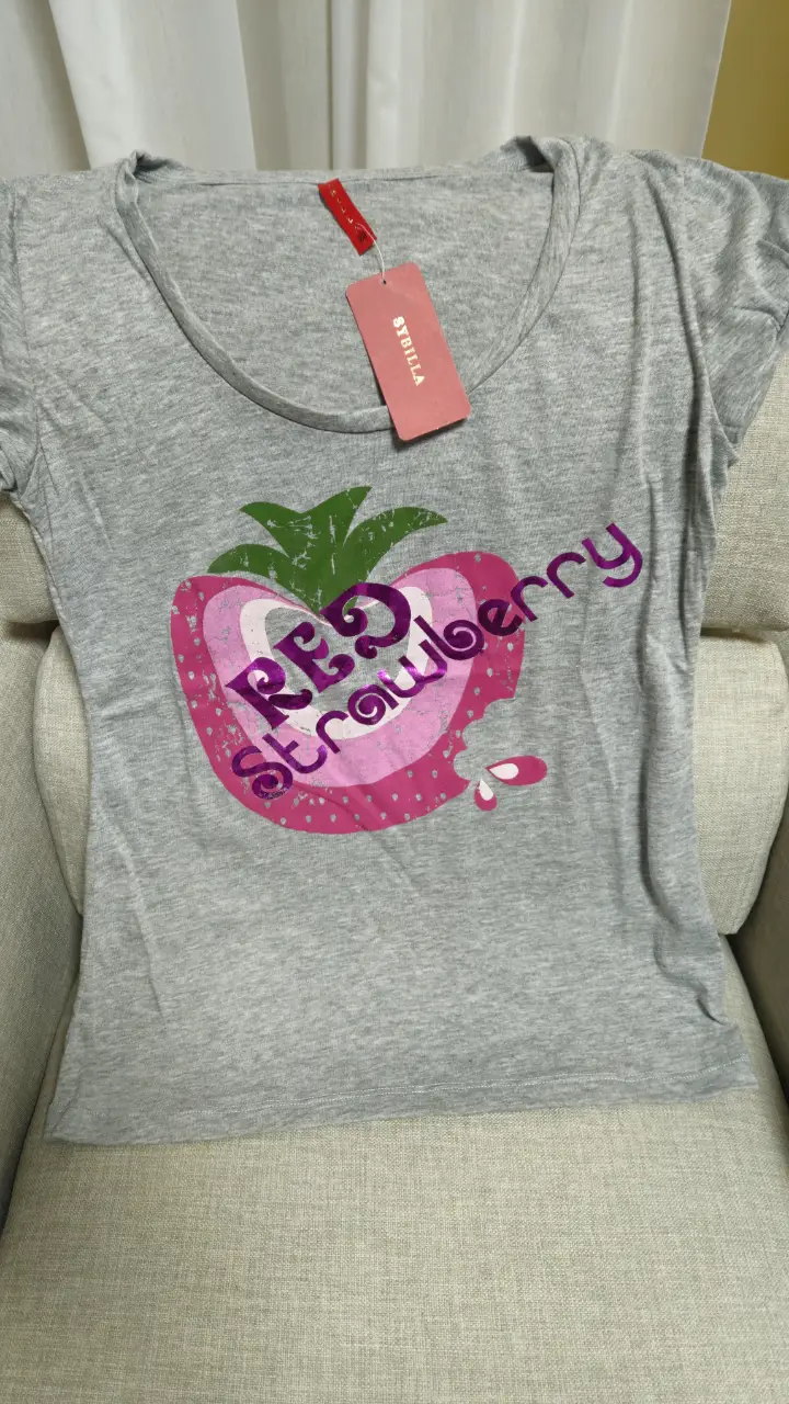 Remera gris de mujer con estampado de frutilla roja y la palabra "RED strawberry" en color violeta. Ideal para un look casual y fresco.