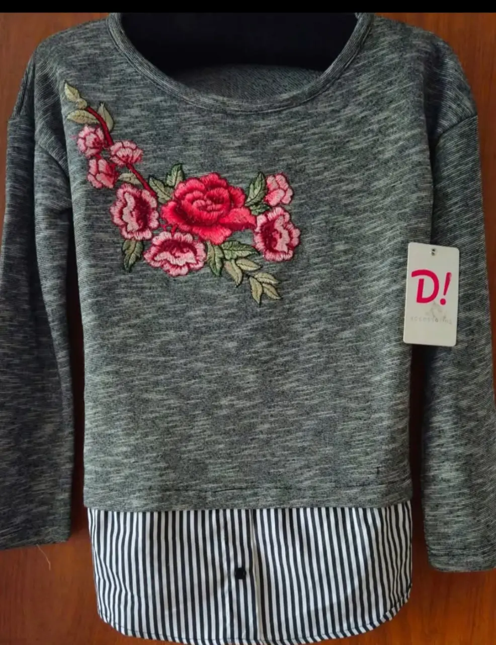 Buzo de cuello redondo gris con detalle de flores bordadas en el frente y un falso diseño de camisa a rayas en la parte inferior. Ideal para un look casual y cómodo.