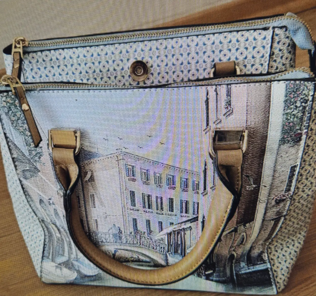 Cartera de mano con diseño de paisaje veneciano. Cuenta con cierre y detalles dorados. Ideal para un look elegante y sofisticado. Corte Inglés.