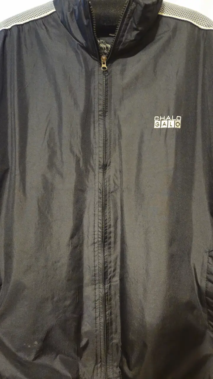Campera deportiva negra con cierre y cuello alto. Tiene detalles en blanco y el logo "CHALO GALO". Interior con forro de piel sintética.
