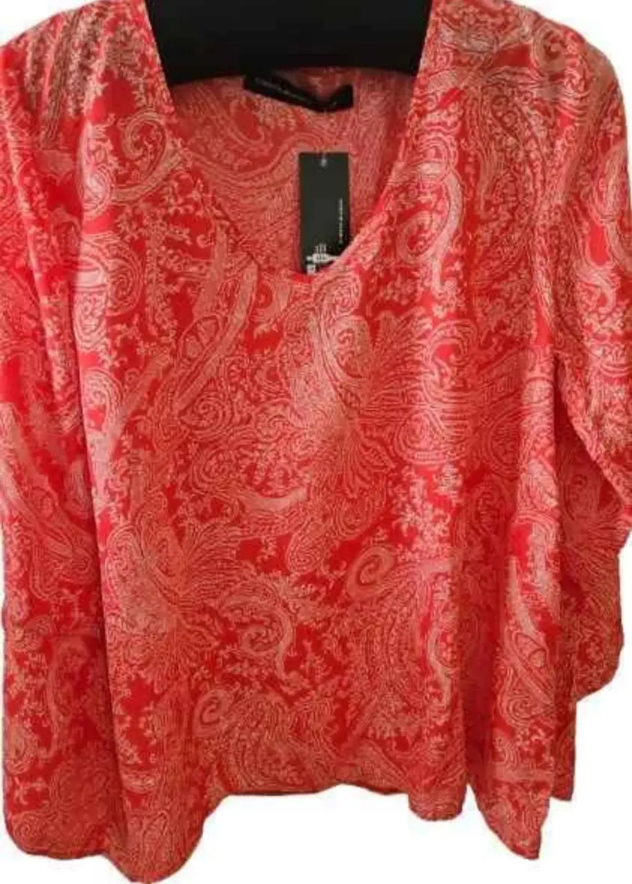 Blusa roja con estampado de diseño paisley. Cuello en V y mangas 3/4. Ideal para un look elegante y sofisticado.