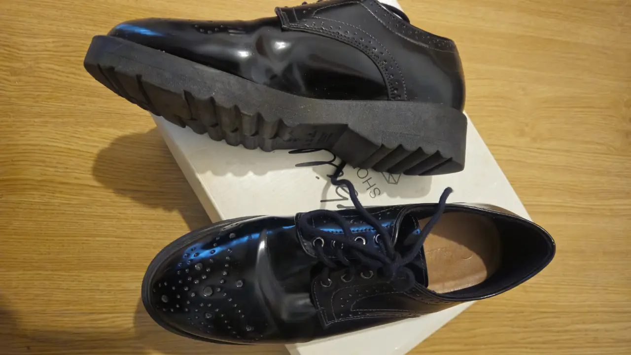 Zapatos de vestir negros de charol con cordones y suela gruesa. Estilo elegante y moderno, ideales para un look sofisticado.