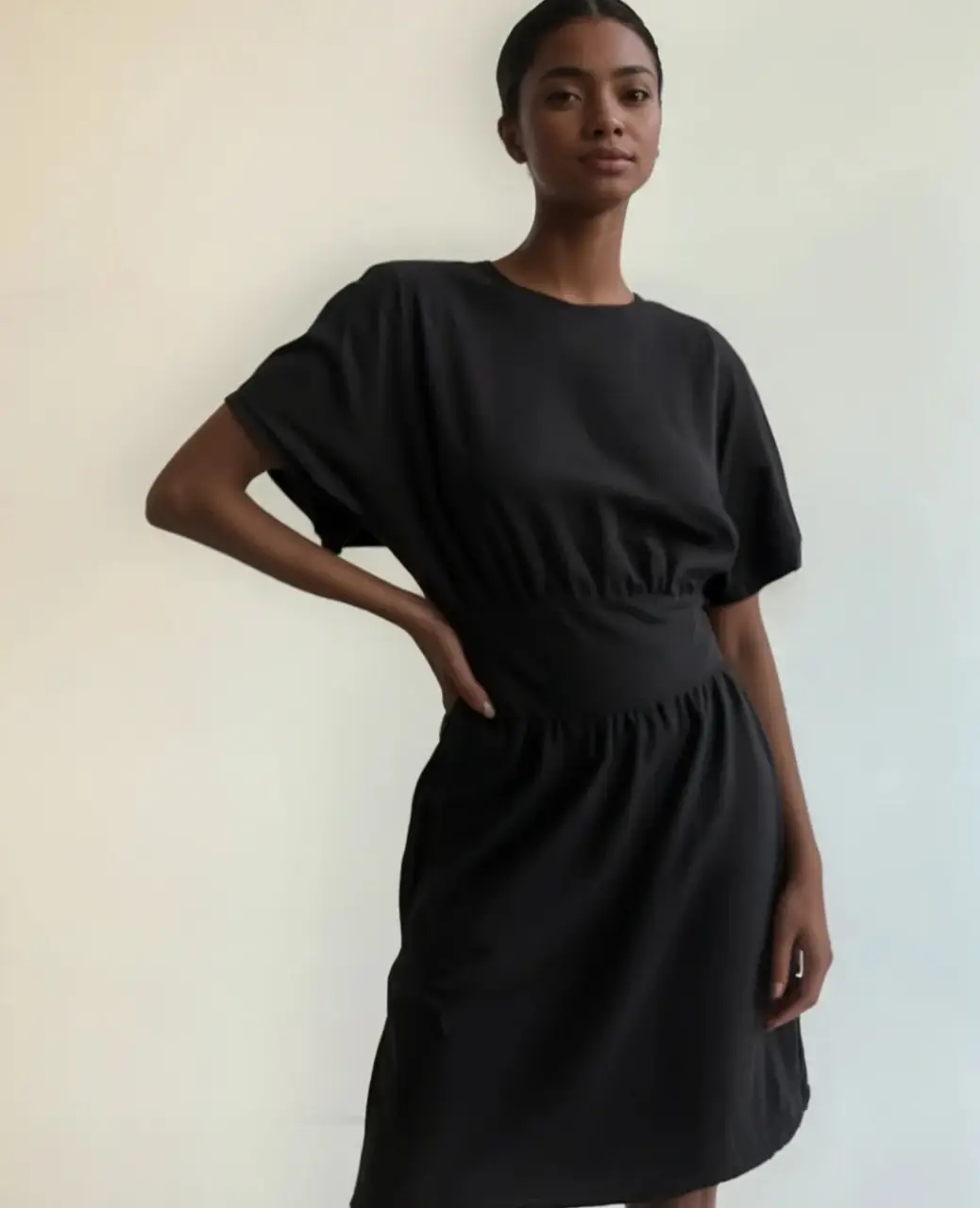Vestido midi negro con corte en la cintura y mangas cortas. Ideal para un look casual y cómodo.