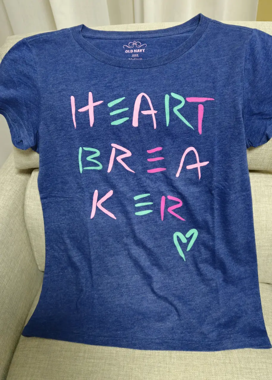 Remera de manga corta azul con estampado "HEART BREAKER" en rosa y verde. Ideal para un look casual y moderno.