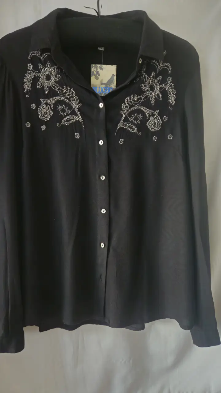 Blusa negra con bordados florales en la parte delantera. Ideal para un look elegante y sofisticado.