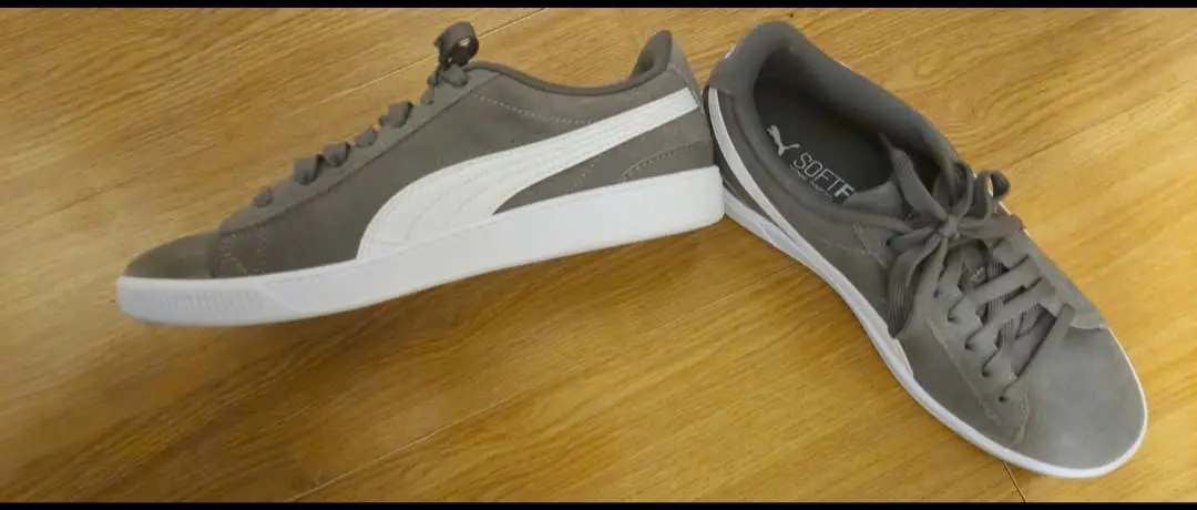 Zapatillas Puma grises con detalles en blanco. Diseño clásico y cómodo, ideales para uso diario.