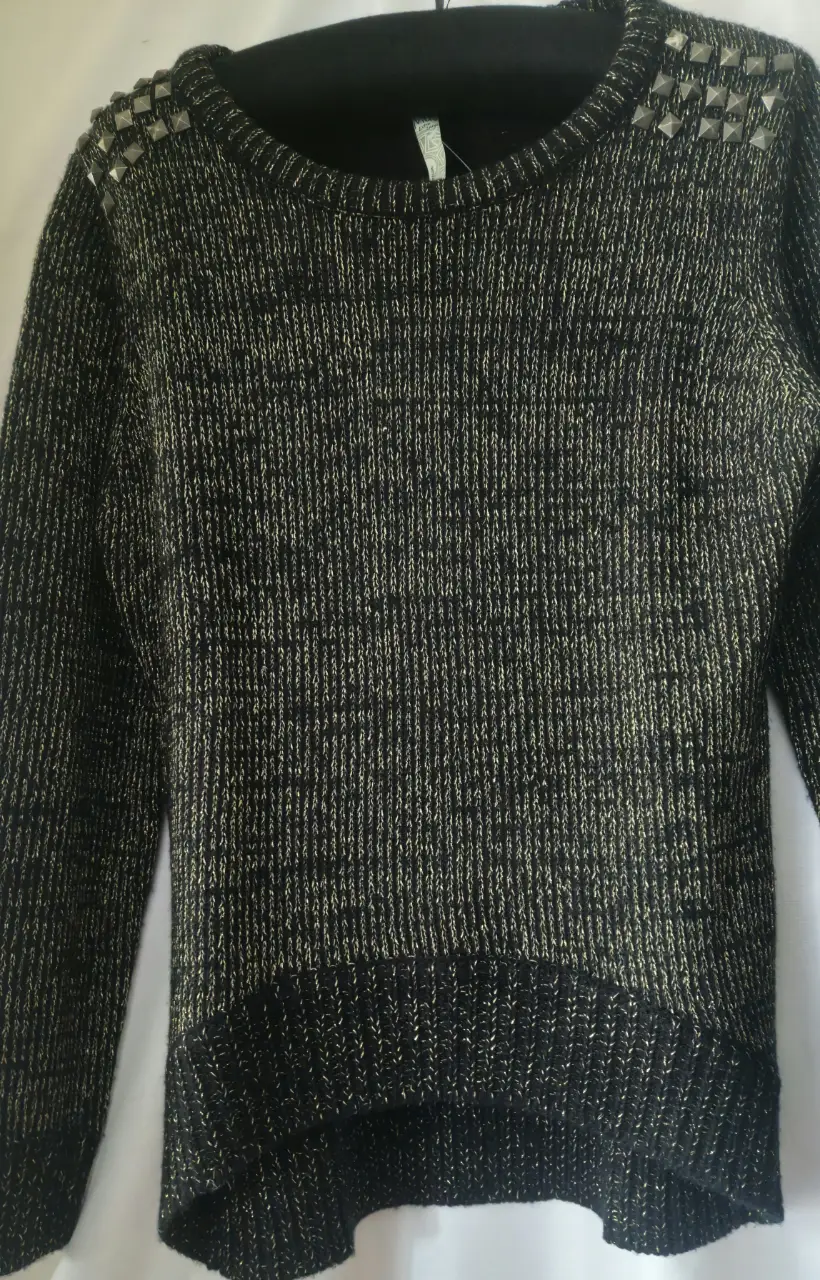 Sweater negro con detalles dorados y tachas en los hombros. Ideal para un look elegante y moderno.