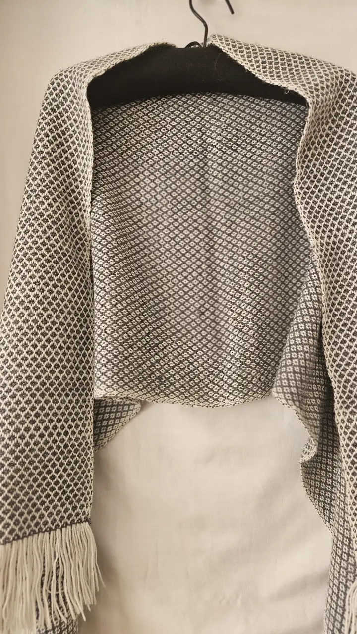 Pashmina  tejida  con diseño de rombos en tonos grises y blancos, ideal para complementar cualquier look con un toque artesanal y abrigado. 160*55 cm .