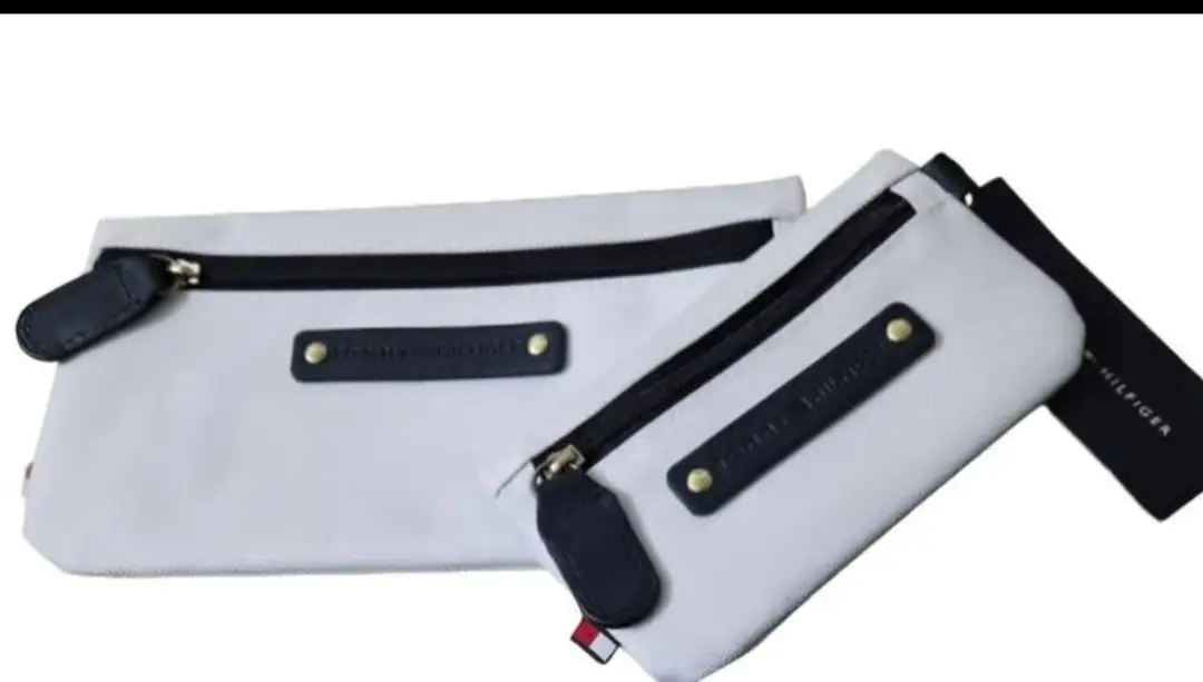 Set de neceseres Tommy Hilfiger blancos con detalles en azul. Incluye dos tamaños diferentes, ideales para organizar tus pertenencias con estilo y practicidad. Cierres y detalles de la marca. Medida 20*10 y 14*7 cm 