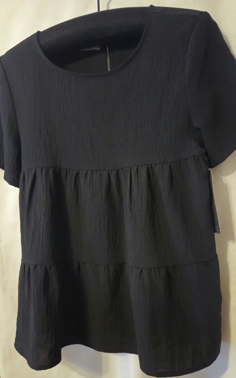 Blusa negra con diseño de volados y mangas cortas. Ideal para un look casual y cómodo.