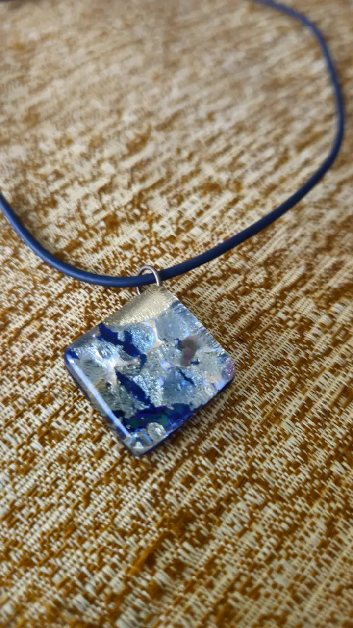 Collar artesanal con dije de vidrio en forma de rombo, con detalles en azul y plateado. Ideal para un look casual o para darle un toque de originalidad a tu outfit.