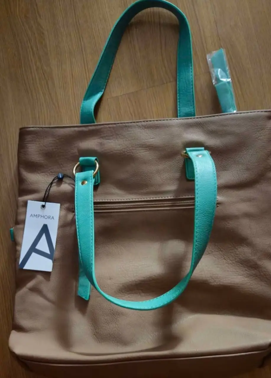 Bolso tote Amphora de cuero sintético marrón con detalles en verde turquesa. Ideal para uso diario, con manijas y correa ajustable. Incluye etiqueta. Medida 40*41*12 cm.
