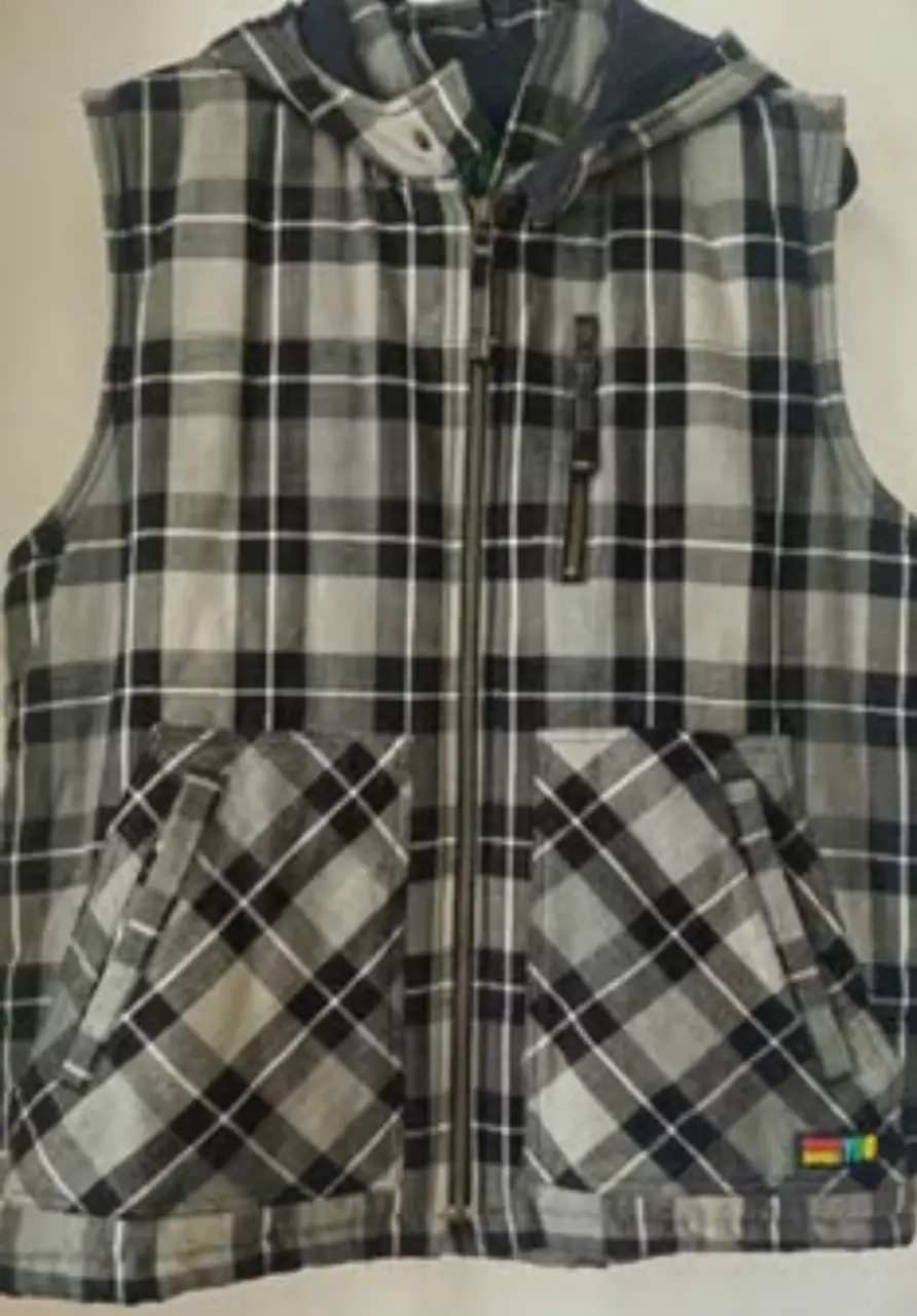 Chaleco con capucha y cierre frontal, diseño a cuadros en tonos grises y negros. Bolsillos delanteros amplios y etiqueta de la marca en la parte inferior. Ideal para un look casual y abrigado.