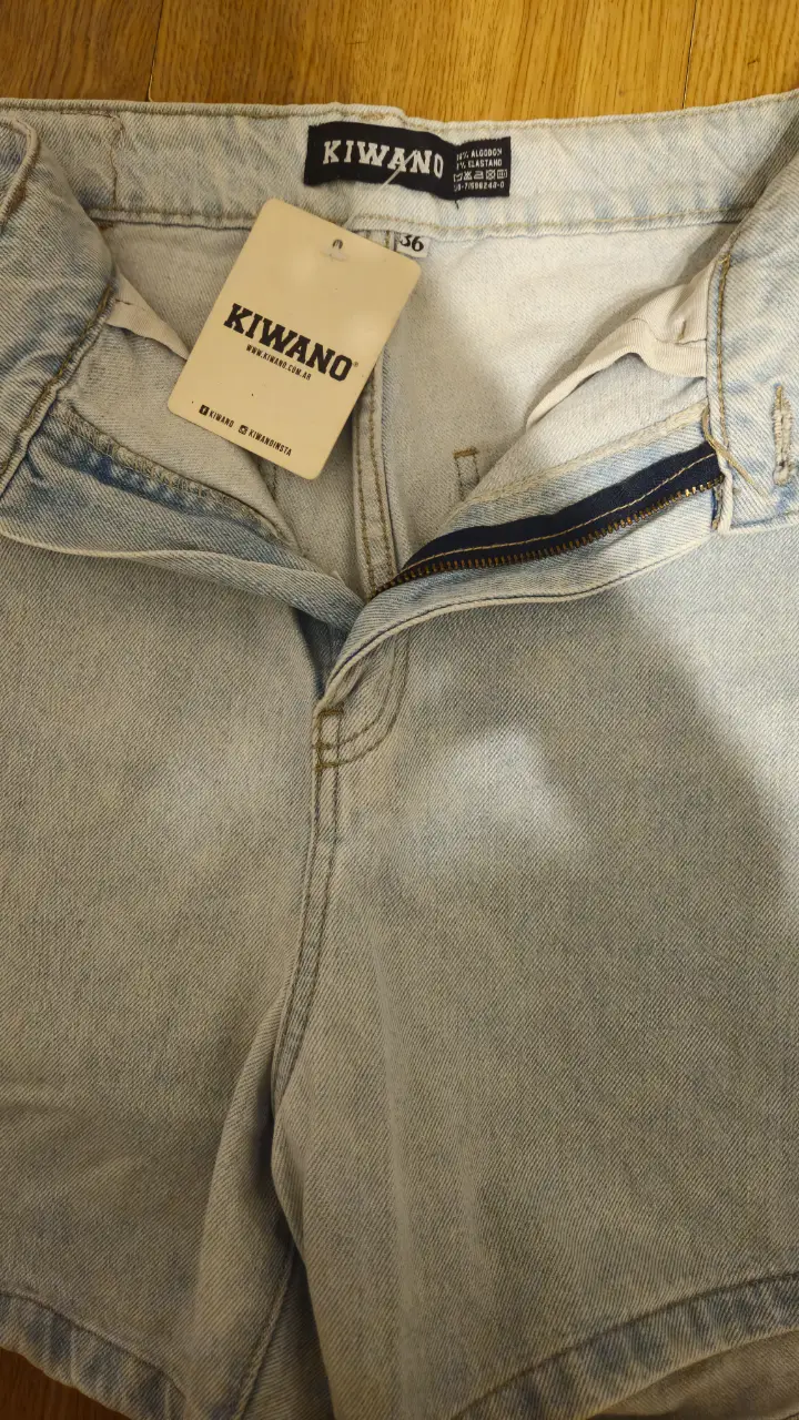 Short de jean celeste claro, tiro medio, con etiqueta de la marca Kiwano. Ideal para un look casual y fresco.