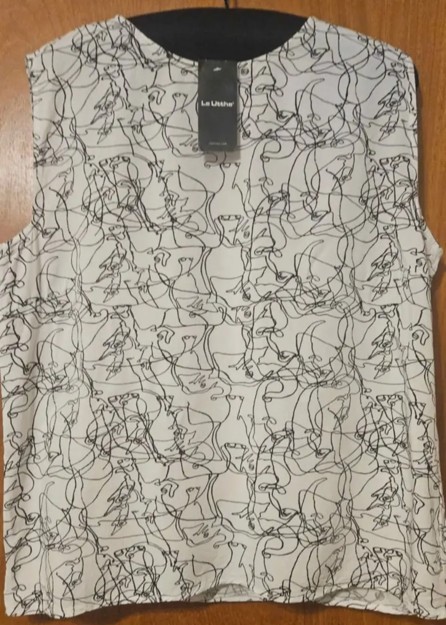 Blusa sin mangas con estampado abstracto en blanco y negro. Cuello redondo y detalle de etiqueta de la marca. Ideal para un look moderno y sofisticado.