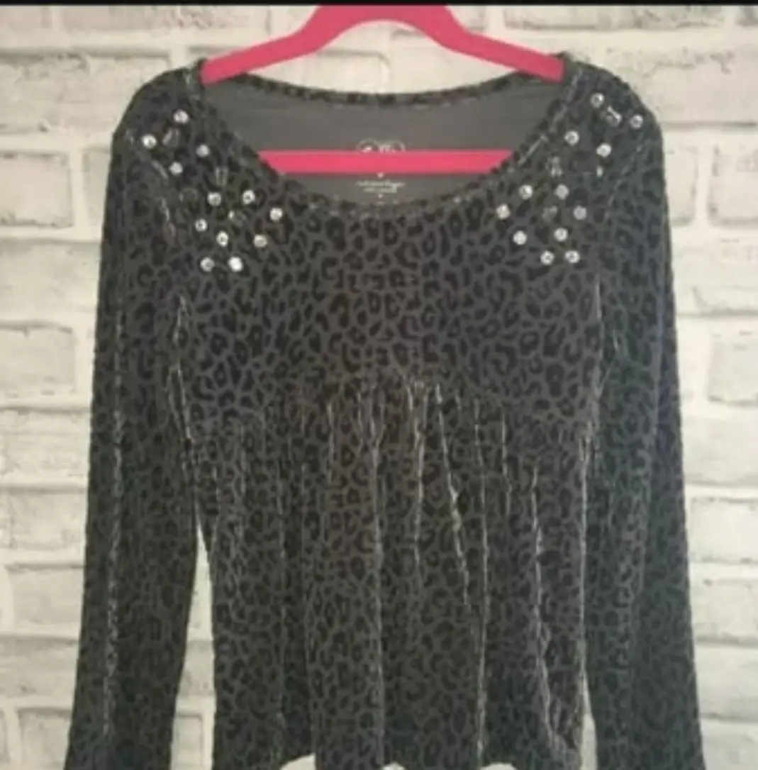 Blusa de terciopelo con estampado de leopardo en tonos grises. Detalles de pedrería en los hombros. Ideal para un look elegante y sofisticado.