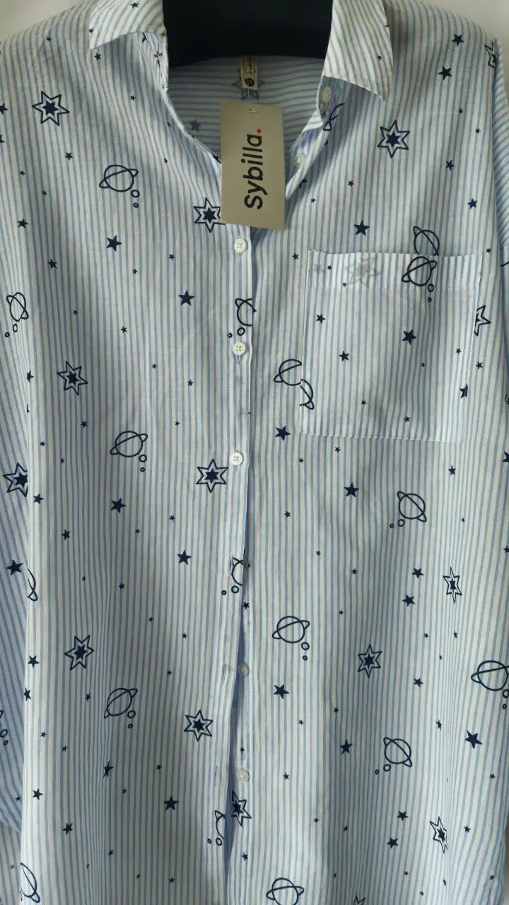 Camisa de mujer con estampado de estrellas y planetas, a rayas celestes y blancas. Marca Sybilla. Con bolsillo en el pecho.