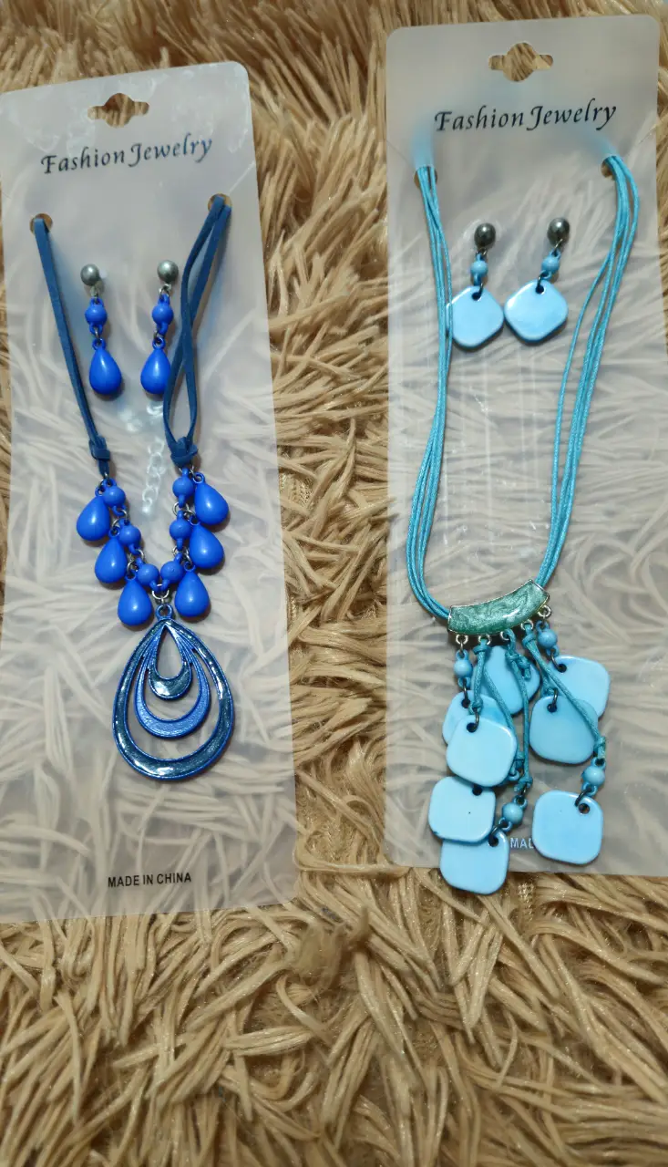 Conjunto de collar y aros de fantasía en color azul. El collar presenta un diseño con dijes colgantes y los aros son a juego. Ideal para complementar cualquier look.