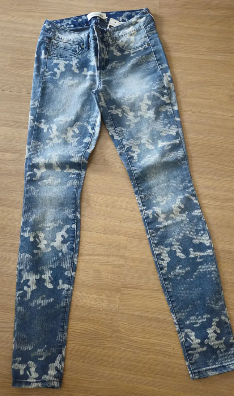 Jeans de mujer tiro alto con estampado camuflado en tonos azules y blancos. Corte skinny, ideal para un look casual y moderno.