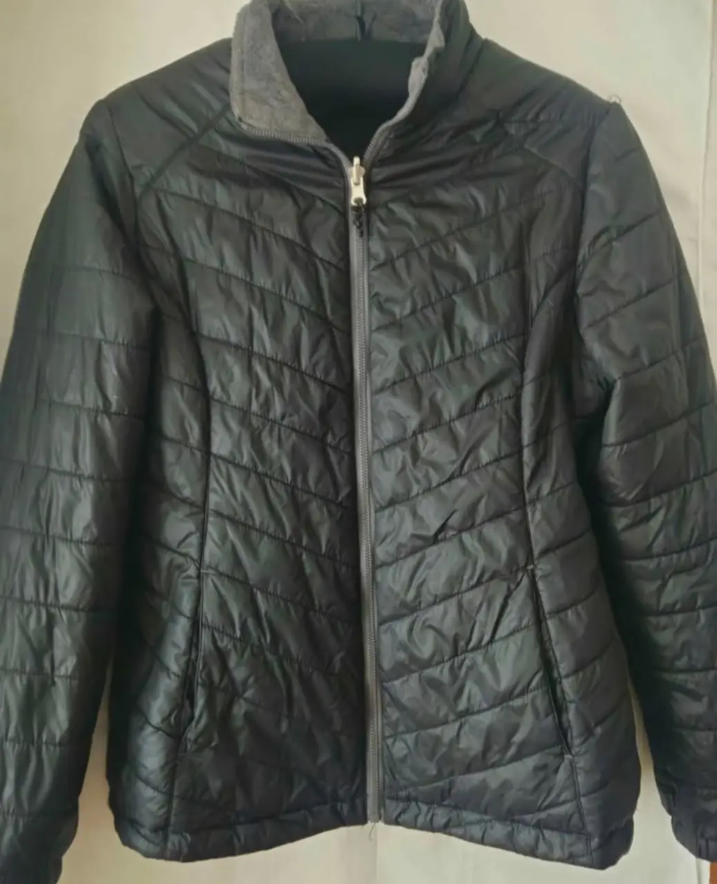 Campera negra acolchada para mujer, ideal para el invierno. Diseño con cierre y cuello alto, perfecta para un look casual y abrigado.