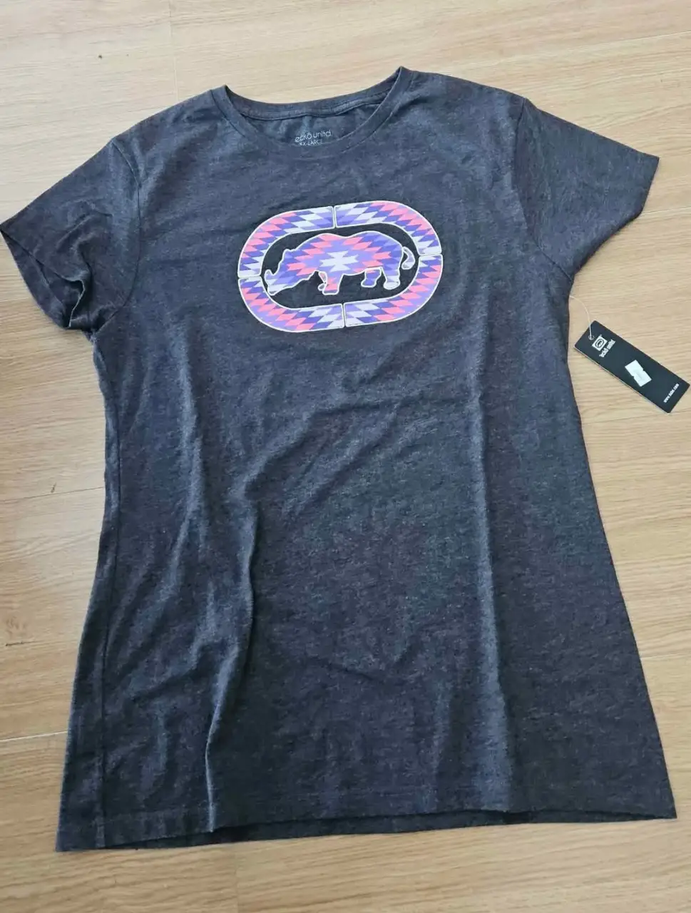 Remera deportiva de mujer, color gris, con estampado en el frente. Ideal para un look casual y cómodo.