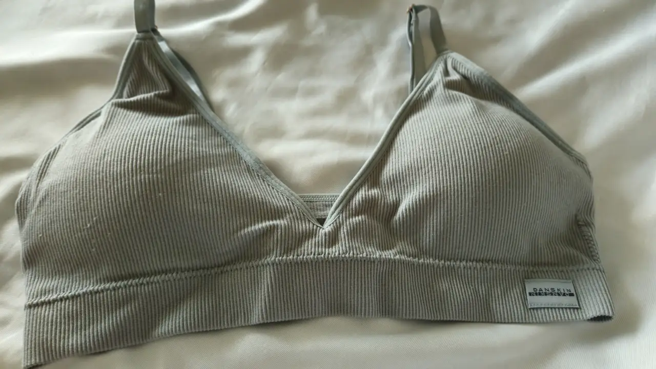 Top deportivo de mujer, color gris, con diseño acanalado y tirantes ajustables. Ideal para actividades de bajo impacto.