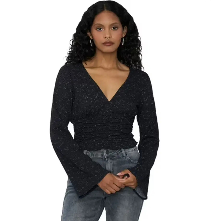 Blusa negra con mangas largas acampanadas y escote en V. Diseño drapeado en la cintura para un ajuste favorecedor. Ideal para un look elegante y moderno.