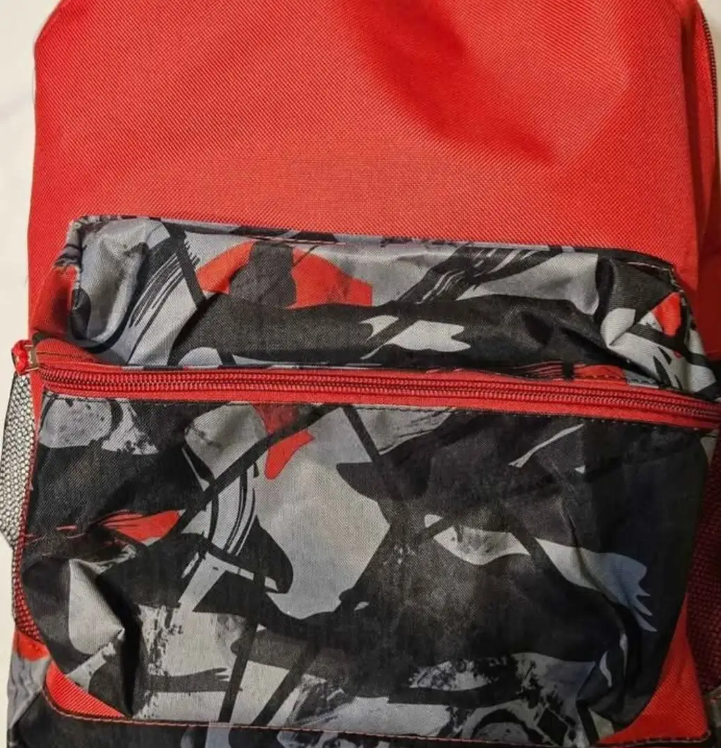 Mochila roja con bolsillo frontal estampado en tonos grises, negros y rojos. Ideal para uso diario o actividades al aire libre.