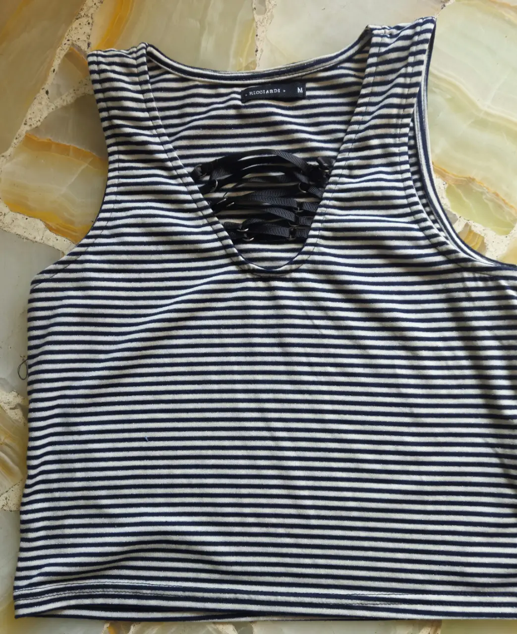 Musculosa de mujer a rayas horizontales en blanco y negro . Diseño con escote en V y detalle de lazada en el centro. Ideal para un look casual y fresco.