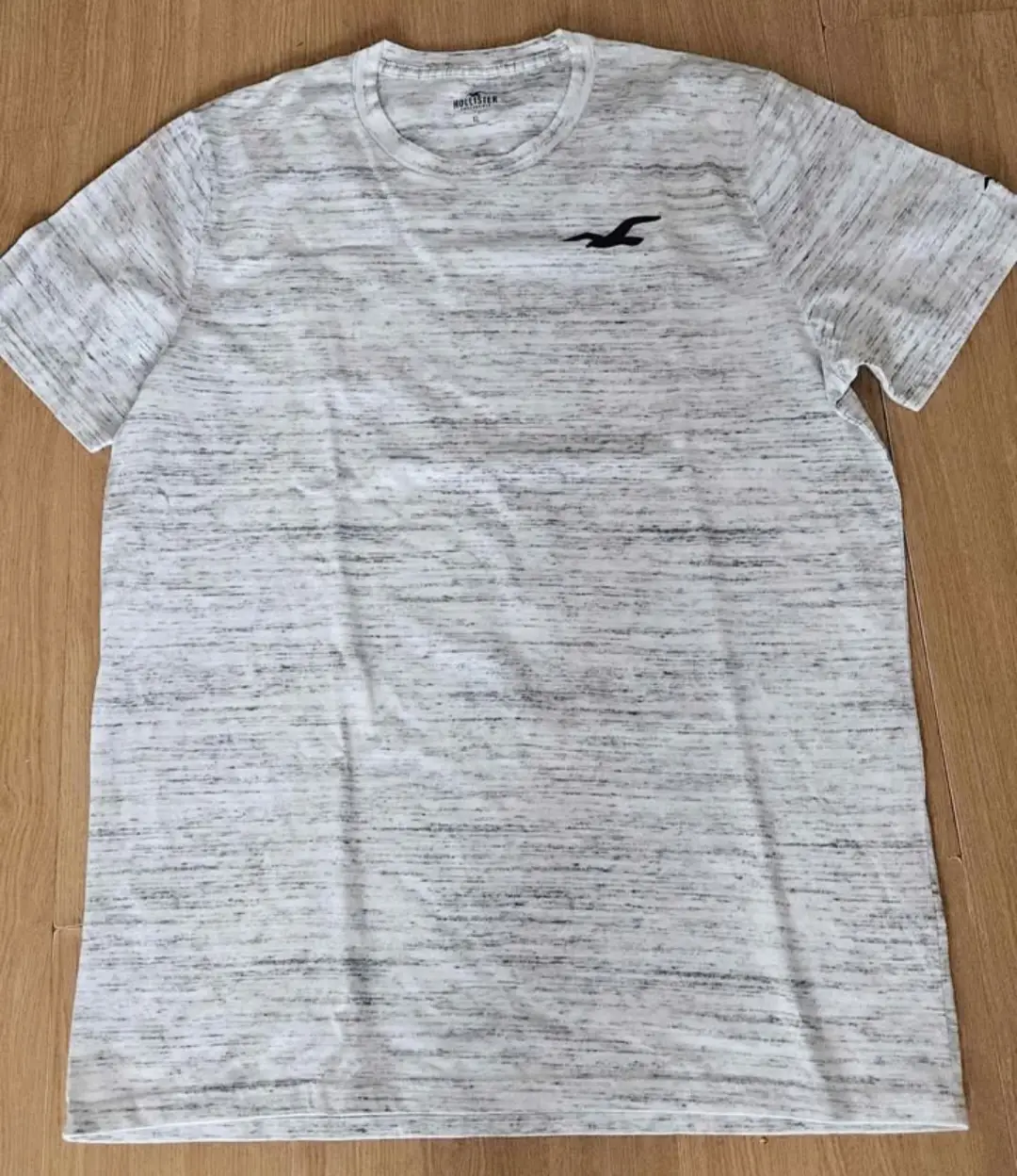 Remera Hollister para hombre, de manga corta, con estampado de logo en el pecho. Confeccionada en tejido jaspeado, ideal para un look casual y cómodo.