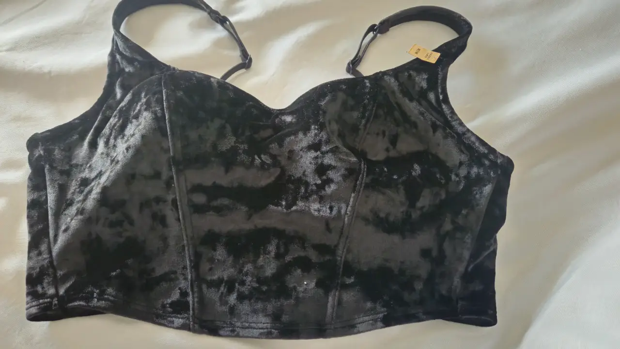 Corpiño negro de terciopelo con detalles de costura y tirantes ajustables. Ideal para un look elegante y sofisticado.