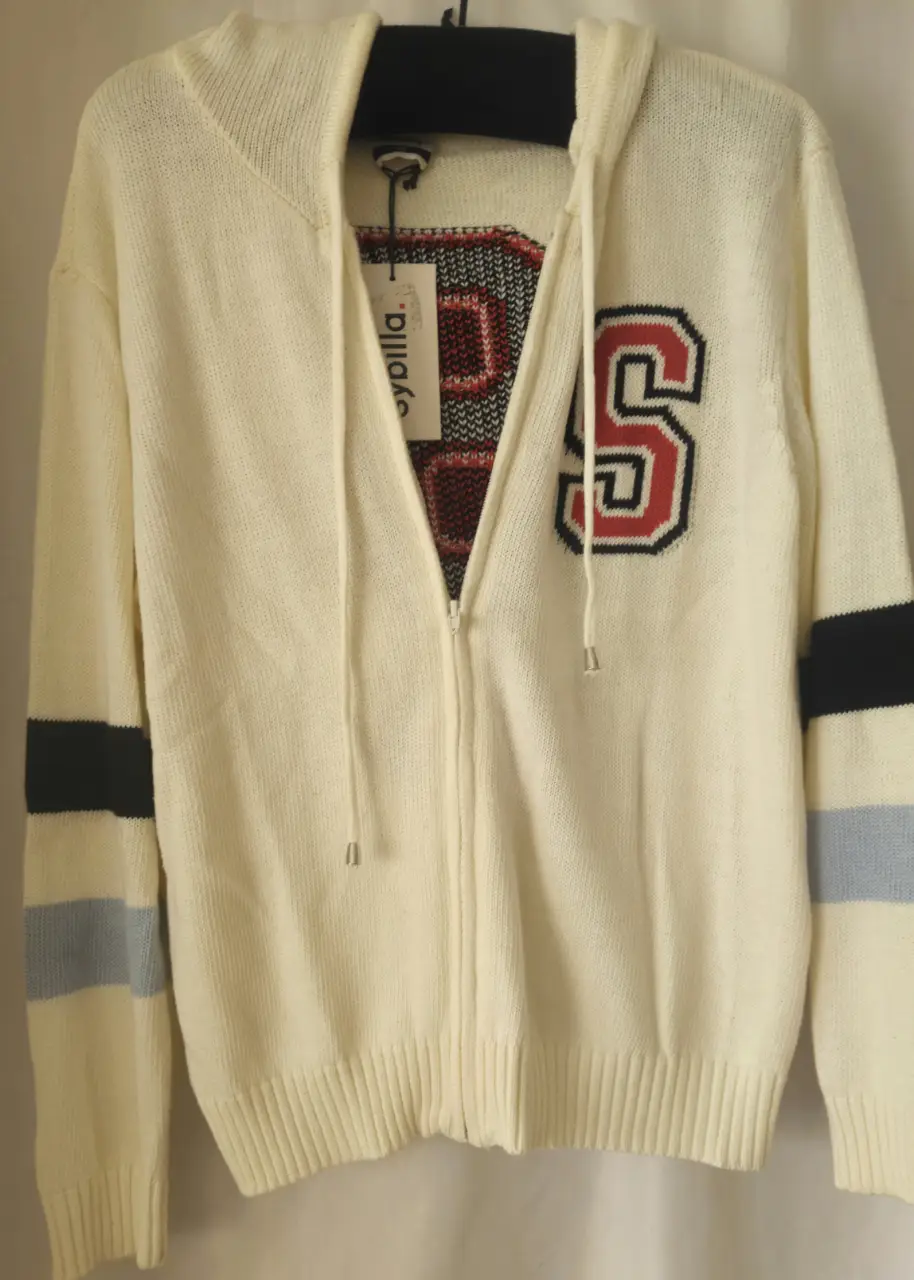 Buzo con cierre y capucha, de color blanco con detalles en rojo y azul. Tiene un aplique con la letra "S" en el frente y la palabra "College" en la espalda. Ideal para un look casual y deportivo.