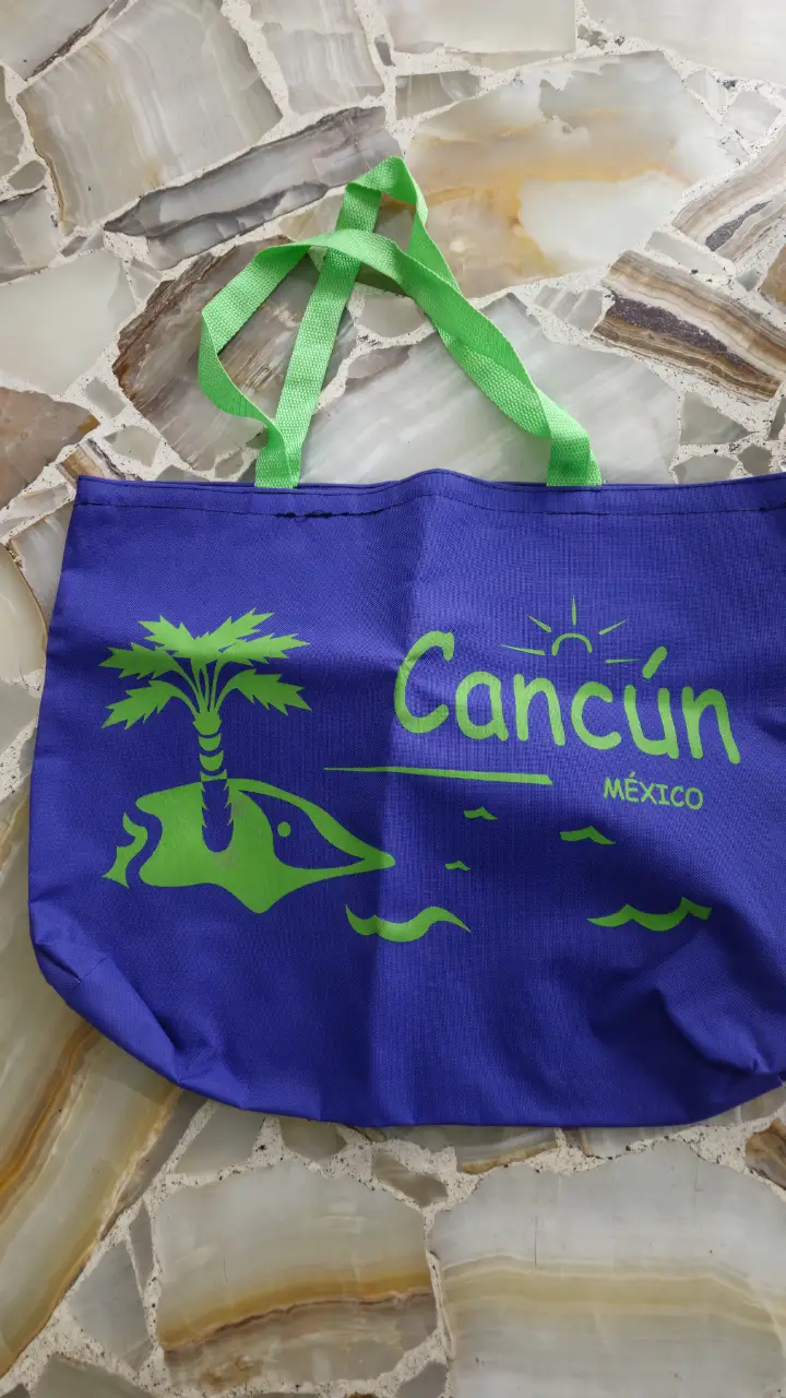 Bolso de playa de tela azul con asas verdes y estampado de Cancún en color verde. Ideal para llevar todo lo necesario a la playa o pileta.