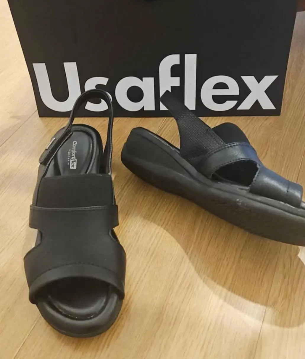 Sandalias Usaflex negras, con ajuste de hebilla y diseño moderno. Ideales para un look casual y cómodo.