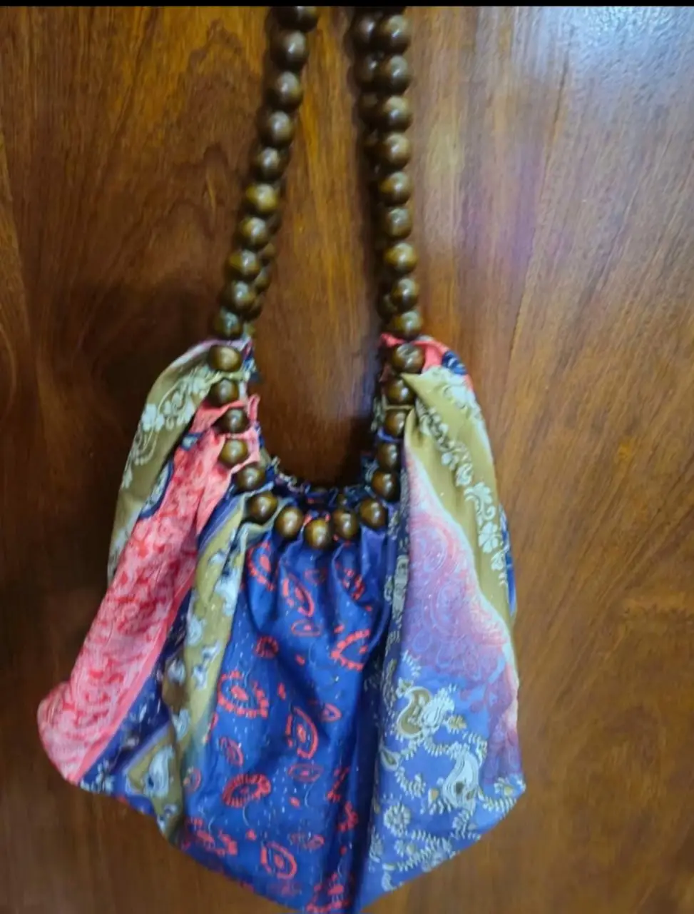 Cartera artesanal con manija de madera y tela estampada. Ideal para un look bohemio y casual.