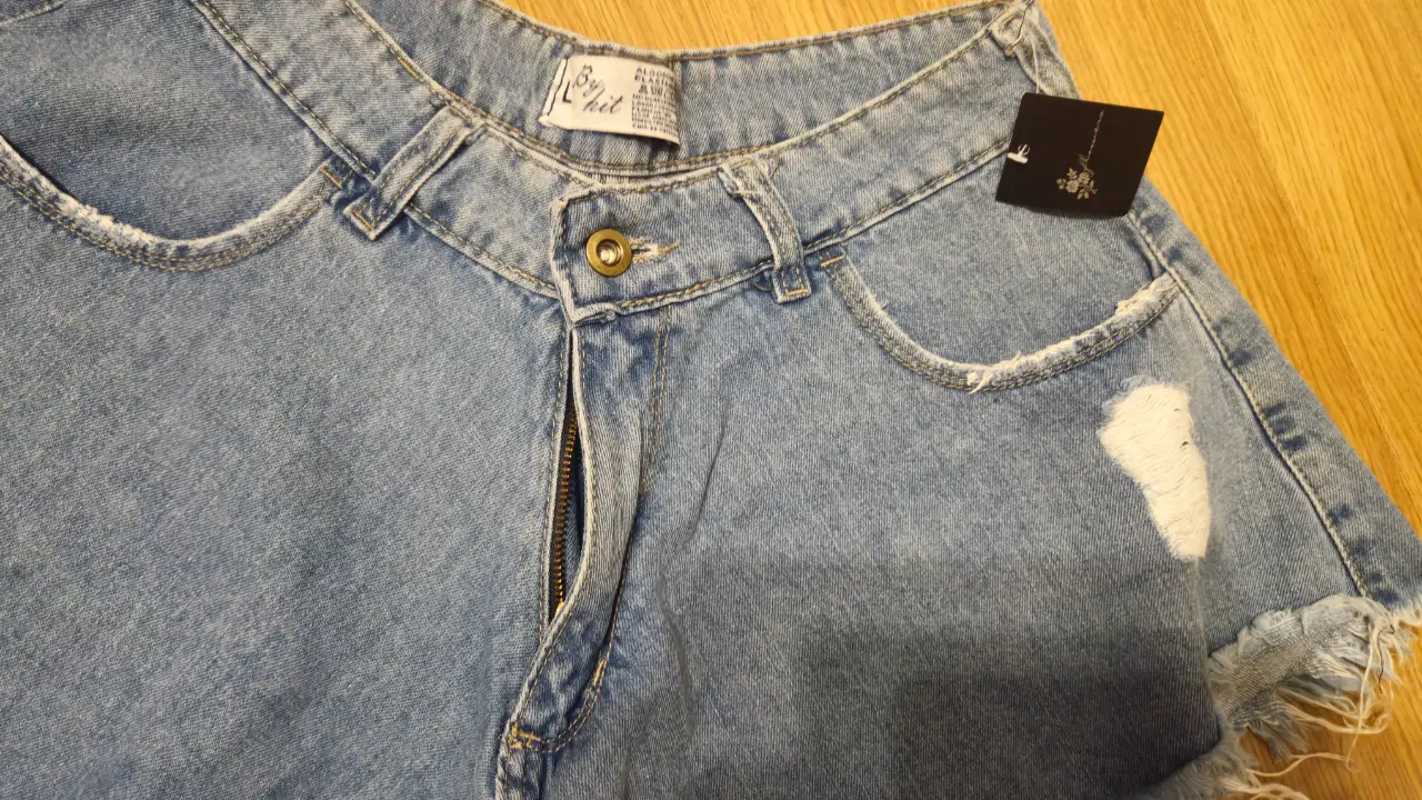 Short de jean de mujer, tiro alto, con roturas y flecos en el borde. Ideal para un look casual y moderno.