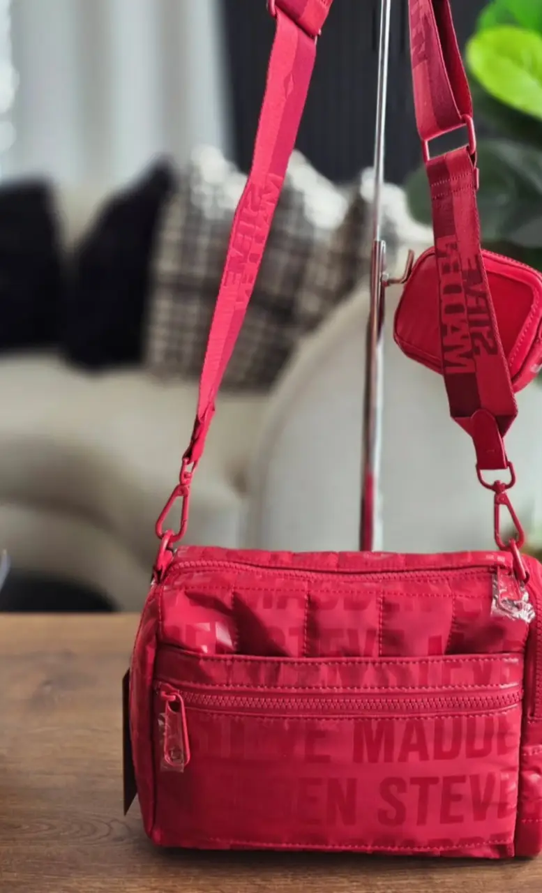 Cartera bandolera roja de la marca Steve Madden, con un diseño acolchado y un pequeño monedero a juego. Ideal para un look moderno y urbano. Medida 24*23*7 cm.