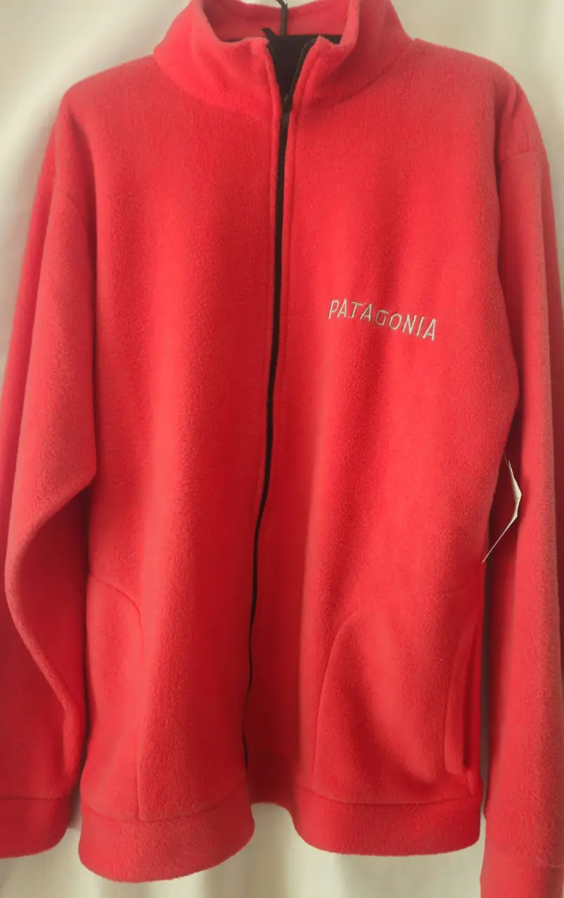 Buzo con cierre rojo de polar, con el logo de Patagonia bordado en blanco. Talle XL.