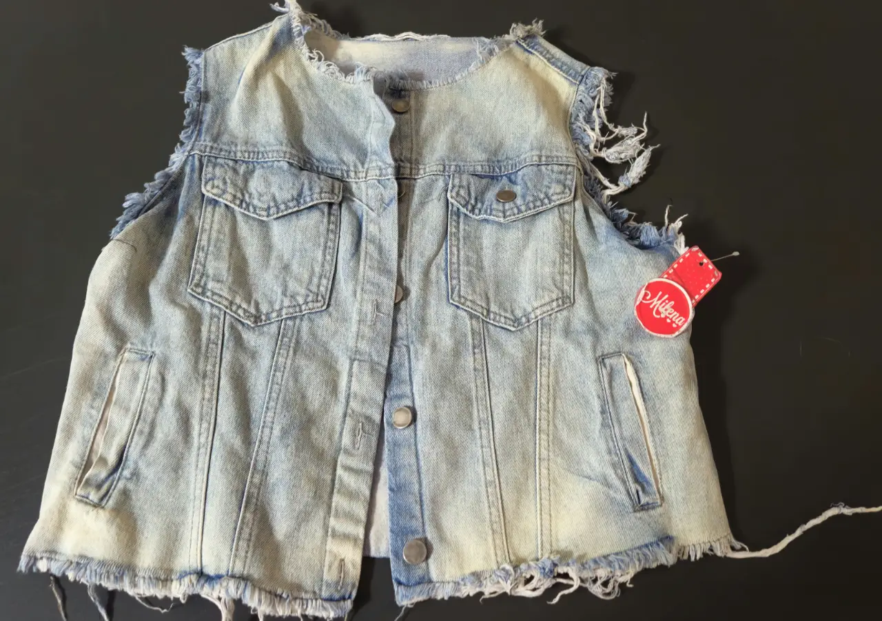 Chaleco de jean azul claro con detalles desflecados. Estilo vintage, ideal para un look casual y canchero. Perfecto para combinar con remeras y camisas.